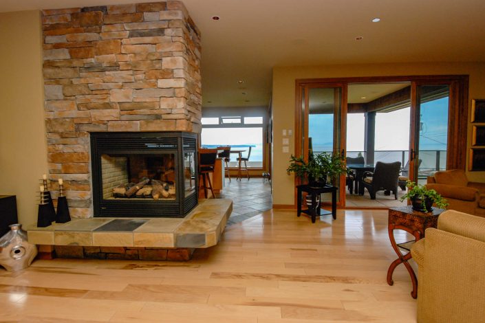 A photo of the living room and three sided fireplace, of a cedar shake estate home built by Surfside Construction