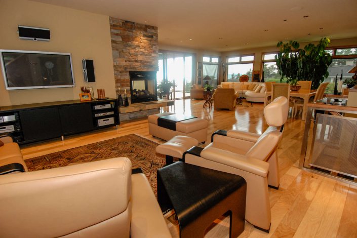 A photo of the living room and three sided fireplace, of a cedar shake estate home built by Surfside Construction