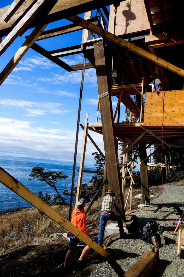A photo of Owen Poppy and crew placing a large beam in the lighthouse home in the sooke bc as built by surfside construction inc.