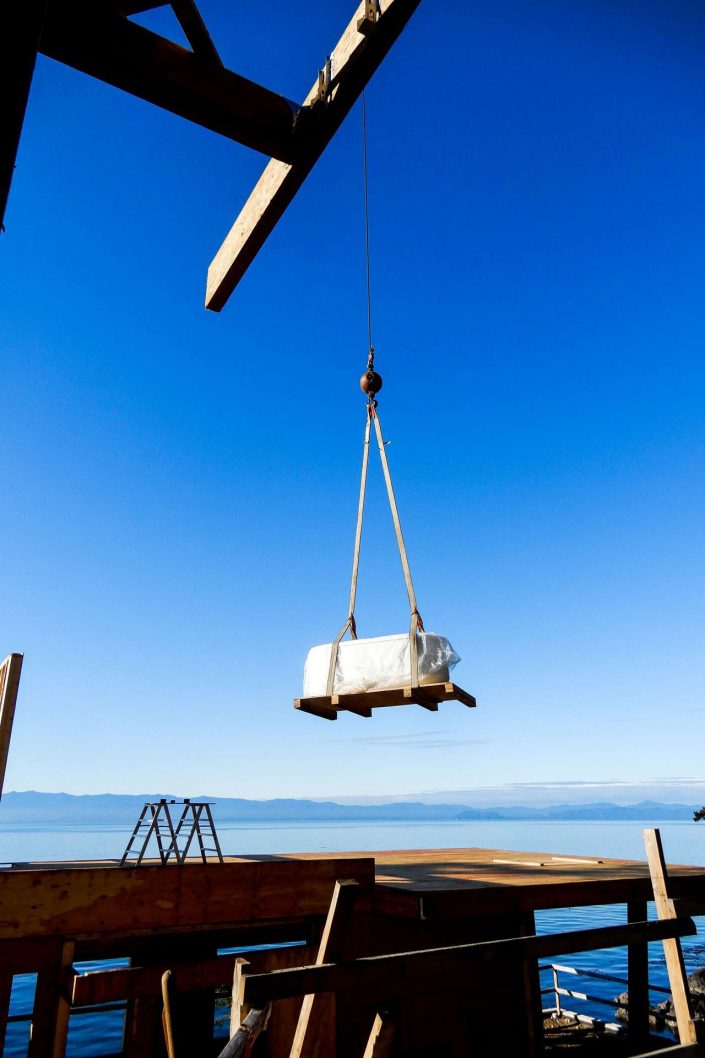 A photo of wood material being boomed over to the lighthouse home in the sooke bc as built by surfside construction inc.