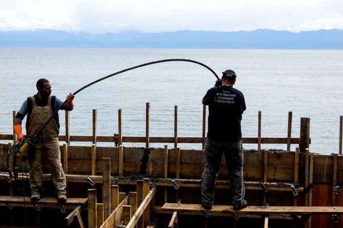 a photo of two of the crew pouring concrete for the foundations of the lighthouse home as built by surfside construction inc.