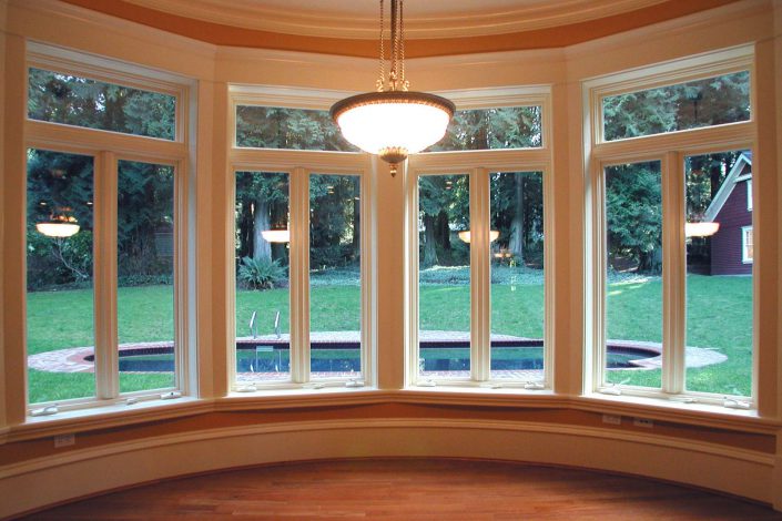 A photo of the large bow window of the victorian replica and the view of the backyard.