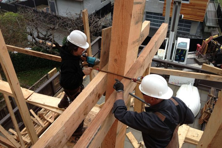 a photo of two carpenters working on one of the beams uses in the west beach home as built by surfside construction inc.