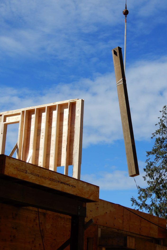 A photo of one of the large, heavy beams being raised into the lighthouse home in sooke bc as built by surfside construction inc.