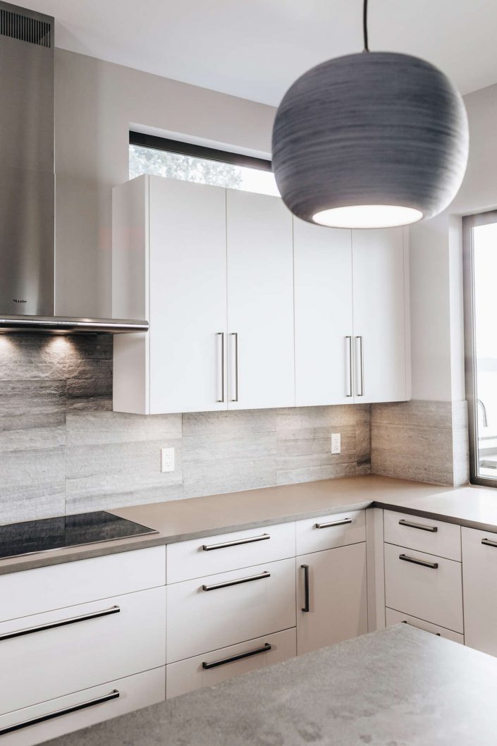 A photo of the kitchen in the hillside modern home showing the clean lines and white cabinets as built by surfside construction inc.