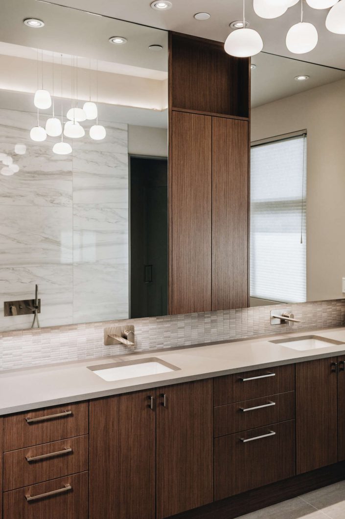 A photo of the ensuite bathroom showing the cabinets, double sinks and large mirror in the hillside modern home as built by surfside construction inc.