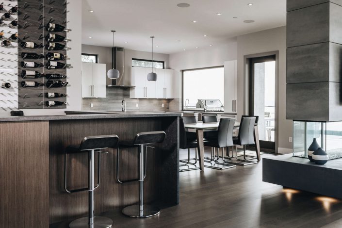 A photo showing the beautiful kitchen, dining room and fireplace in the hillside modern home as built by surfside construction inc.