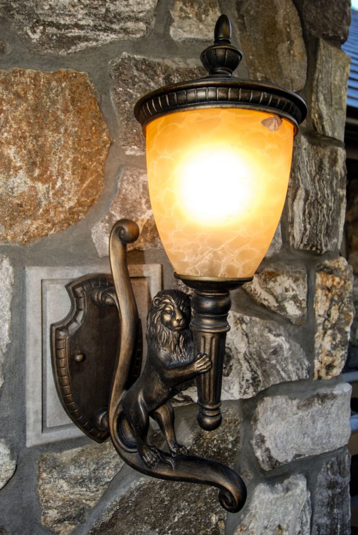 A photo of one of the exterior sconces, a bronze lion holding the light at the entrance to the crescent bluff home as built by surfside construction inc.