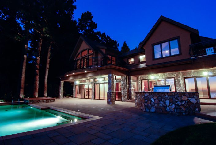 A night shot showing the pool, patio and interior lighting of the crescent bluff home as built by surfside construction inc.